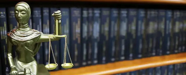 Estátua da Justiça diante da estante de livros do escritório